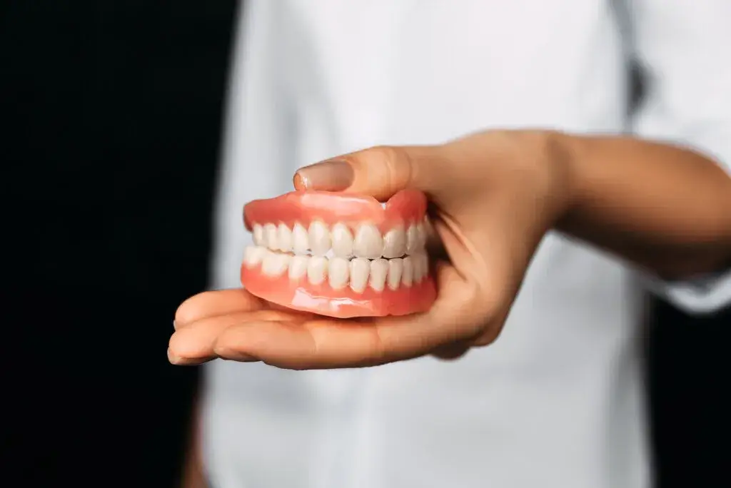 dentist-holding-a-sample-of-auburn-traditional-dentures